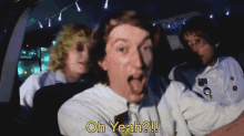 a man in a white shirt is driving a car and says oh yeah