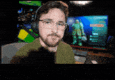 a man wearing headphones looks at the camera in front of a computer screen