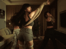 a woman in a crop top and shorts is dancing in a living room