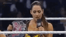 a woman is standing in a wrestling ring with a microphone in her hand .