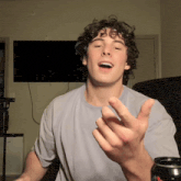 a young man with curly hair is making a funny face in front of a flat screen tv