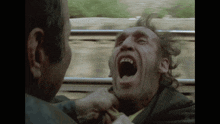 a man with his mouth wide open is being punched by another man