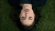 a woman laying on her back in the grass with smoke coming out of her mouth .