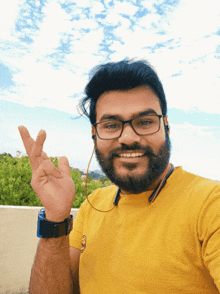 a man wearing glasses and a yellow shirt with the number 3 on it makes a peace sign