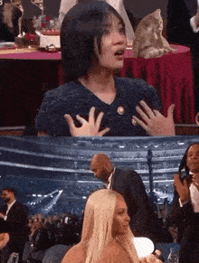 a woman is crying while sitting in front of a crowd at a awards show .