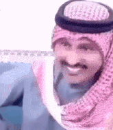 a close up of a man wearing a pink head scarf and a hat .