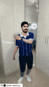 a man wearing a blue and white striped shirt is standing in front of a mirror