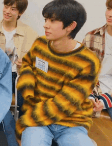 a boy wearing a yellow and black striped sweater with a name tag
