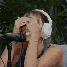 a woman wearing headphones is covering her face while singing into a microphone