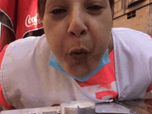 a woman wearing a mask is blowing a kiss in front of a coca cola sign