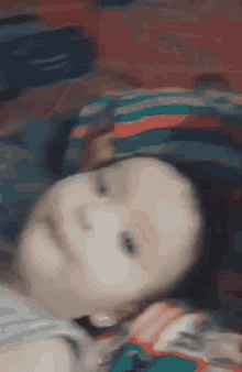 a baby is laying on a bed with a striped shirt on and making a funny face .