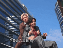 a man in a suit is holding another man in a chair with chinese writing on the bottom