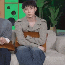 a young man is sitting on a couch with his arms crossed and looking at the camera .