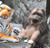 a stuffed tiger sits next to a stuffed monkey on a rock