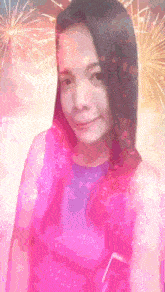 a woman in a pink top stands in front of a fireworks display