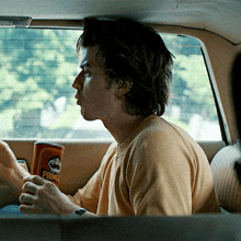 a man in a car holding a can of pringles chips