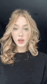a young woman with blonde hair and freckles is wearing a black shirt