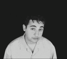 a man in a white shirt is looking at the camera with a black background