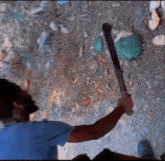a man in a blue shirt is holding a machete in his right hand