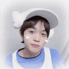 a boy wearing a white hat with paw prints on his cheeks
