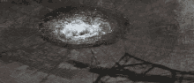 a black and white photo of a manhole cover with water coming out
