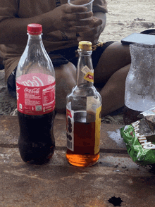 a bottle of coca cola sits on a table next to a bottle of alcohol