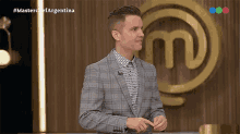 a man in a suit is standing in front of a master chef logo