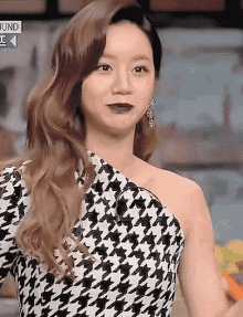 a woman is wearing a black and white houndstooth dress and earrings .