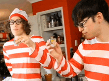 a man in a striped shirt is holding a shot glass
