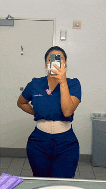 a nurse is taking a selfie in front of a mirror .