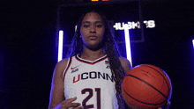 a woman in a uconn jersey holds a basketball in her hands