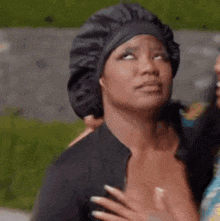 a woman wearing a black hat and a black shirt is making a face .