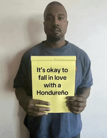 a man holds up a yellow notepad that says it 's okay to fall in love with a hondureno