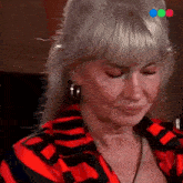 a woman in a red and black striped shirt is crying .