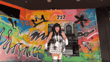 a woman stands in front of a graffiti covered building with the number 217