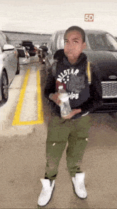 a young boy is standing in a parking garage with a bottle of water in his hand .
