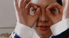 a woman is making a funny face by making a circle with her hands around her eyes .