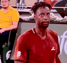 a man is wearing a red shirt with the letter b on it
