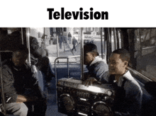 a group of people sitting on a bus holding a boombox with the word television above them