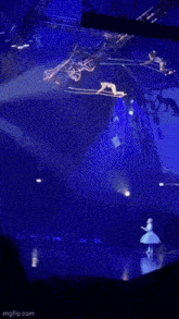 a ballerina is dancing on a stage in front of a crowd while a man is hanging from a crane .