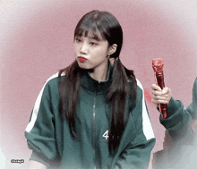 a girl wearing a green jacket with the number 4 on it holds a microphone