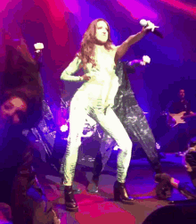 a woman singing into a microphone while dancing on stage