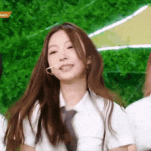 a girl with long brown hair is wearing a white shirt and tie .