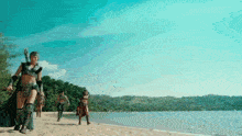 a group of people are walking on a sandy beach near a body of water