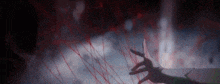 a close up of a person 's hand holding a red string in the dark .