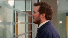 a man in a blue jacket and tie is looking out a window .