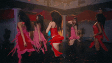 a group of women in pink dresses are dancing