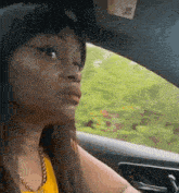 a woman is sitting in the driver 's seat of a car and looking out the window .
