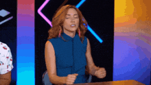a woman in a blue shirt is sitting at a table