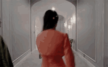 a woman in a red jacket is walking down a hallway with a man .